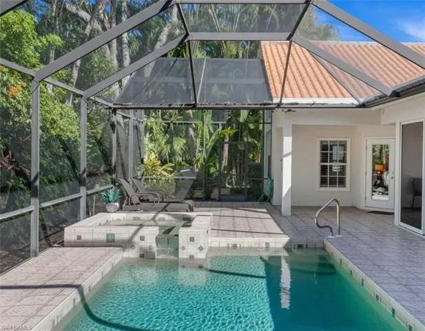Outdoor pool featuring glass enclosure, a sunroom, and a patio