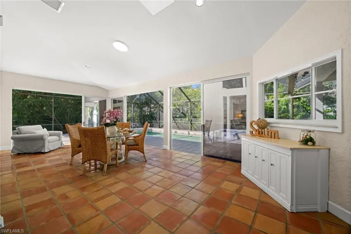 Sunroom / solarium featuring lofted ceiling, plenty of natural light, an outdoor kitchen, and outdoor dining space