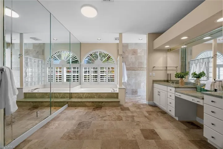 Bathroom with a garden tub, walk in shower, vanity, stone tile floors, and recessed lighting