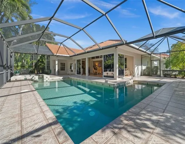 Swimming pool with a sunroom, a lanai, a jacuzzi, and a patio area
