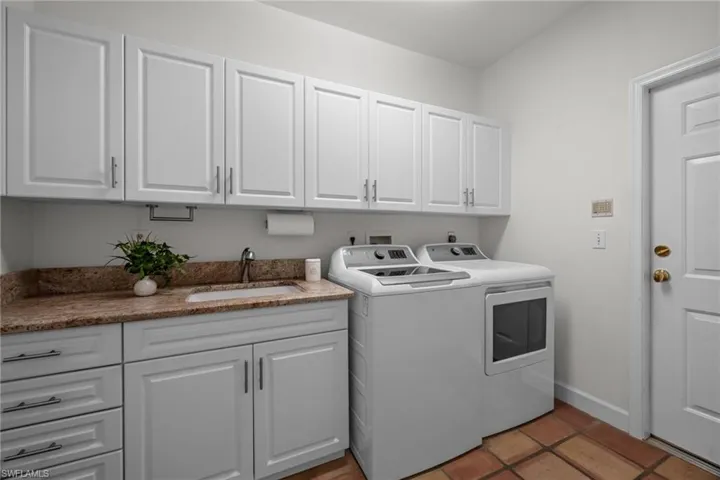 Laundry room featuring cabinet space, washer and dryer, and light tile patterned floors