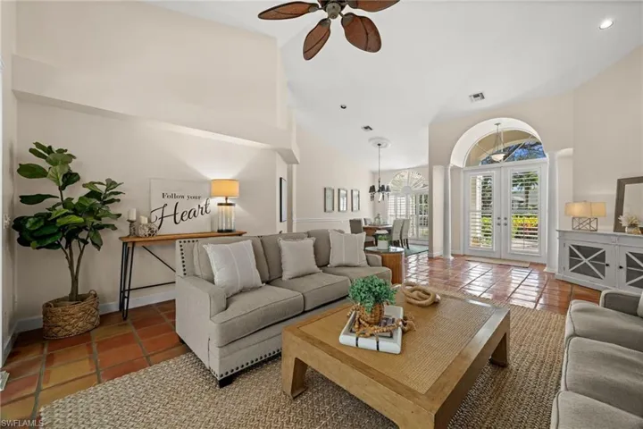 Living area with tile patterned floors, french doors, ceiling fan, and high vaulted ceiling