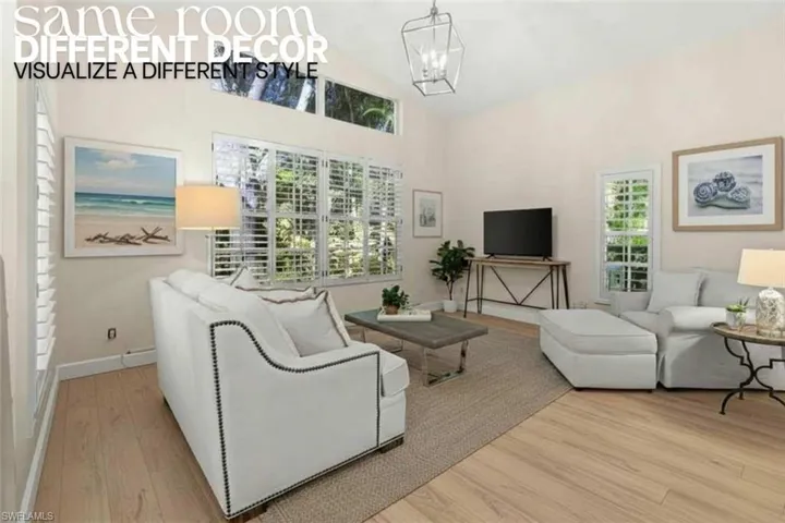 Living room with light wood finished floors, a chandelier, and high vaulted ceiling