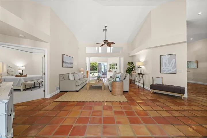 Tiled living room featuring high vaulted ceiling and a ceiling fan