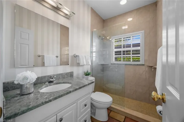 Full bathroom featuring tiled shower, vanity, and tile patterned floors