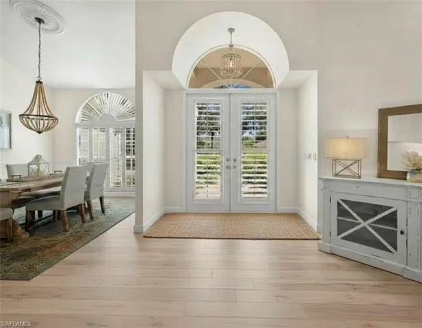 Entrance foyer featuring french doors, a chandelier, and light wood finished floors