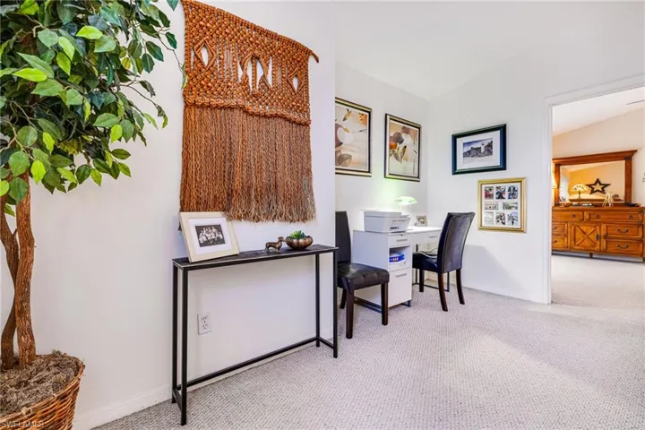 Carpeted home office featuring baseboards