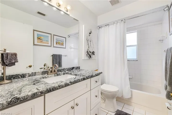 Bathroom featuring shower / bath combo with shower curtain, vanity, and light tile patterned floors