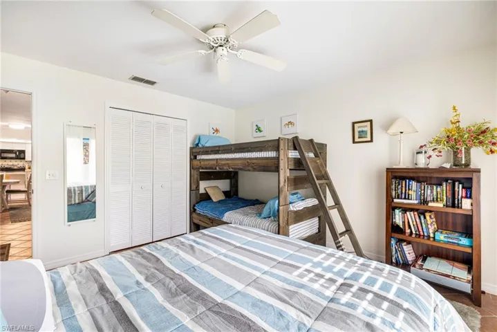 Tiled bedroom featuring ceiling fan and a closet