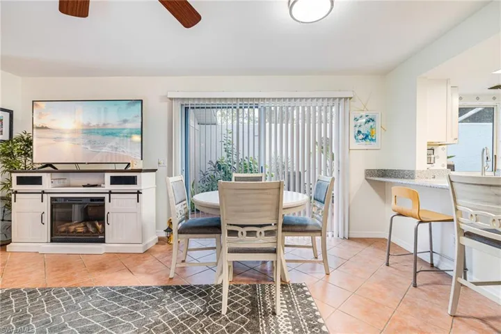 Dining room featuring light tile patterned floors, a ceiling fan, and a glass covered fireplace
