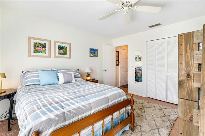 Tiled bedroom with a ceiling fan and a closet