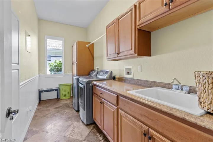 Laundry room with washer and clothes dryer, cabinets, and sink