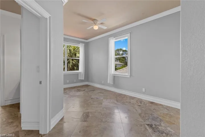 Unfurnished room with ceiling fan, plenty of natural light, and ornamental molding