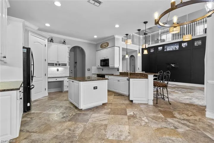 Kitchen featuring a kitchen island, decorative light fixtures, black appliances, tasteful backsplash, and white cabinetry
