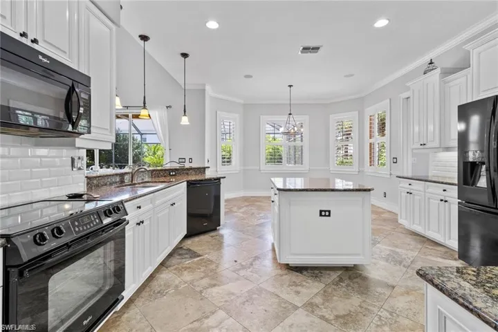 Kitchen featuring white cabinetry, black appliances, and dark stone counters
