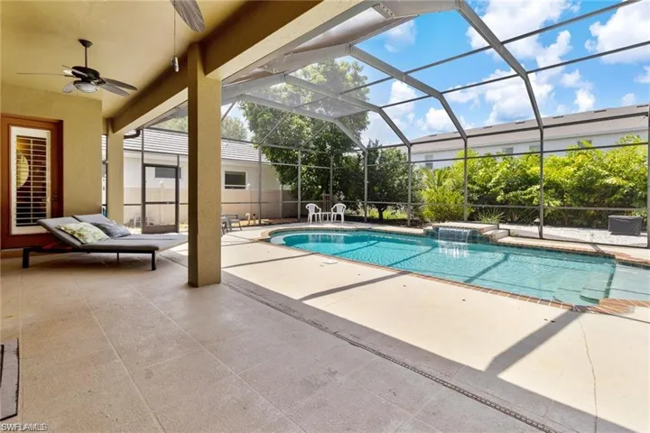 View of pool featuring a lanai, pool water feature, a patio area, and ceiling fan