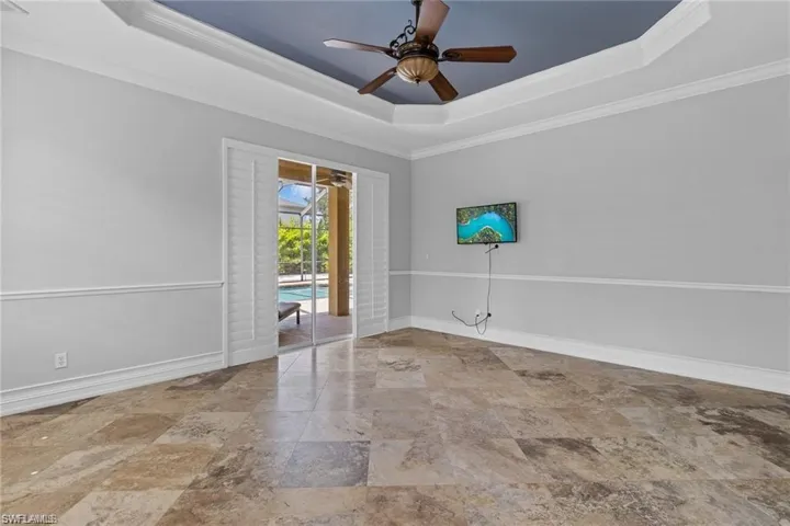 Empty room featuring crown molding, a raised ceiling, and ceiling fan