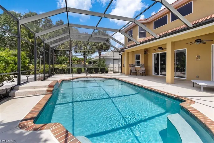 View of pool with a lanai, ceiling fan, and a patio area