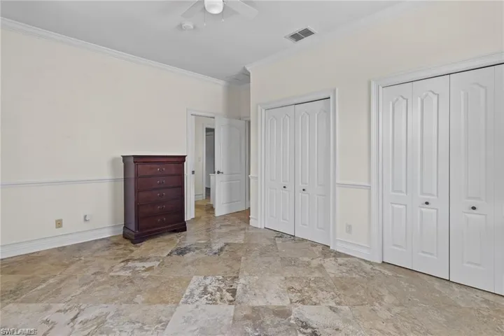 Unfurnished bedroom featuring two closets, ceiling fan, and crown molding