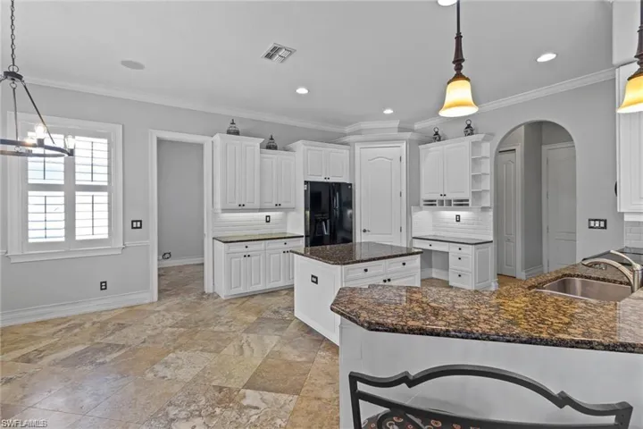 Kitchen with pendant lighting, a kitchen island, sink, and black fridge