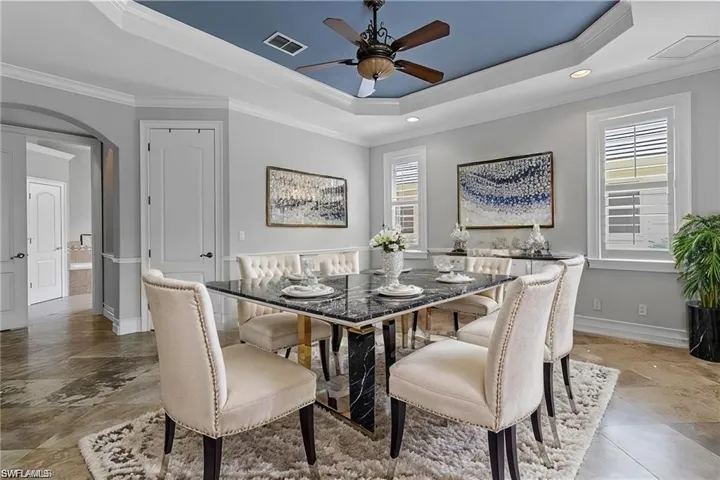 VIRTUAL STAGING  Dining space with a raised ceiling, ceiling fan, and crown molding