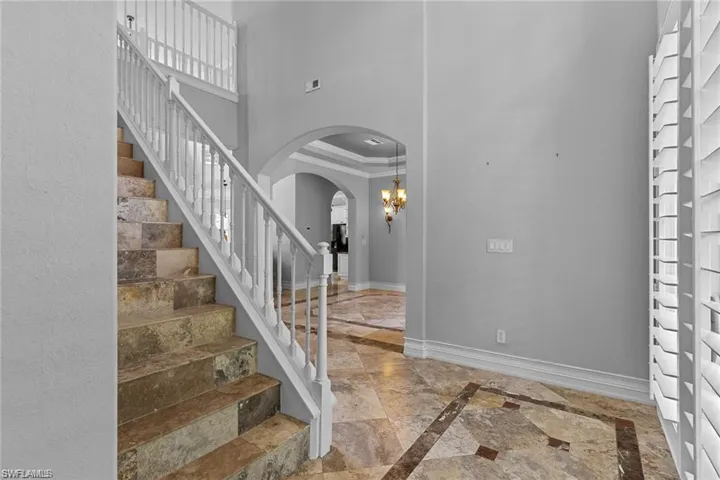 Foyer featuring a chandelier, crown molding, and a towering ceiling