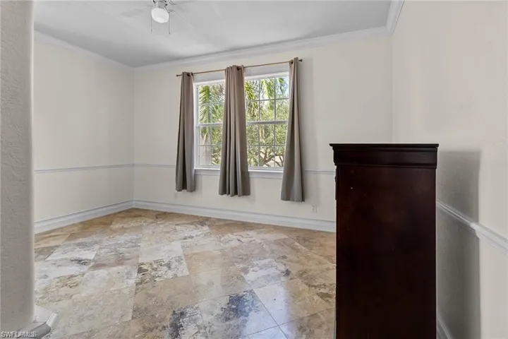 Unfurnished bedroom featuring ceiling fan and ornamental molding