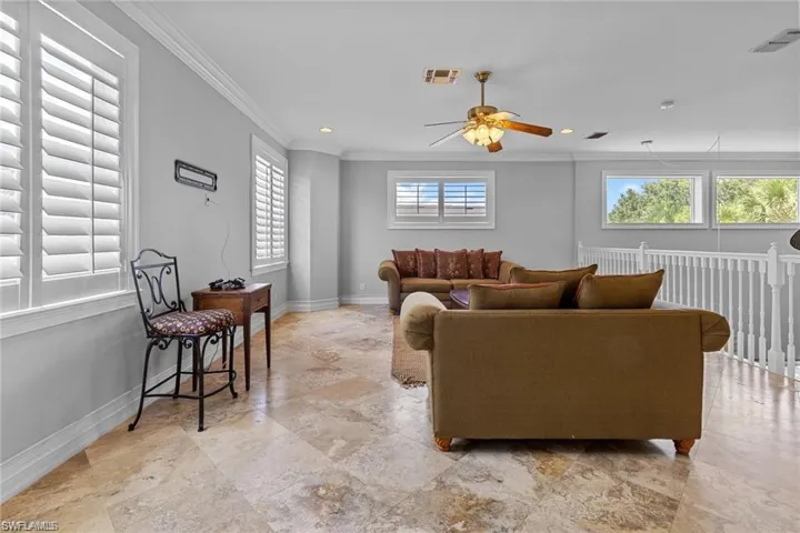 Living room with ceiling fan, ornamental molding, and a healthy amount of sunlight