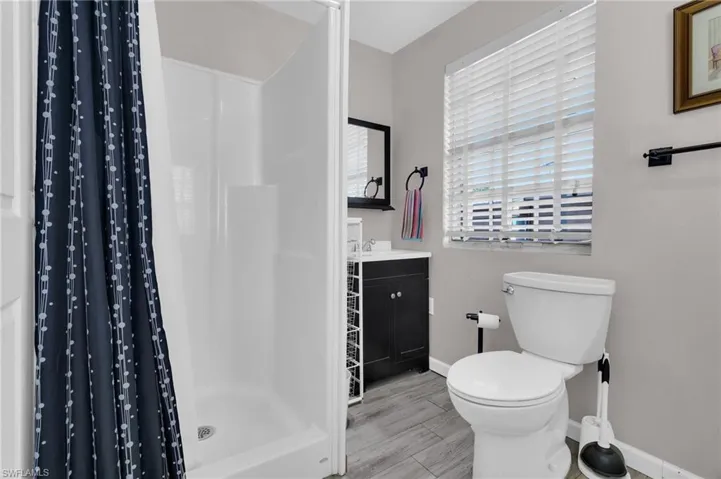 Full bathroom featuring vanity, baseboards, a shower stall, and toilet