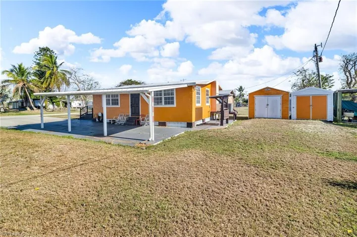 View of front of property featuring entry steps, an outdoor structure, a storage shed, and a back  yard