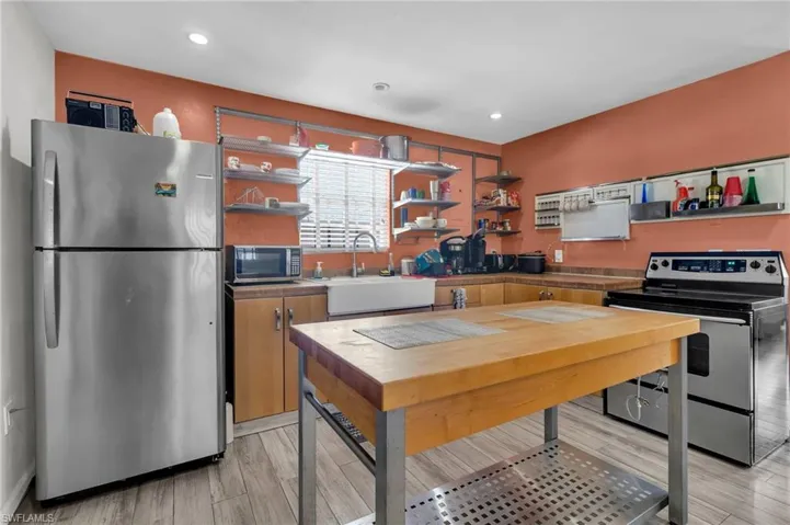 Kitchen featuring open shelves, stainless steel appliances, a sink,