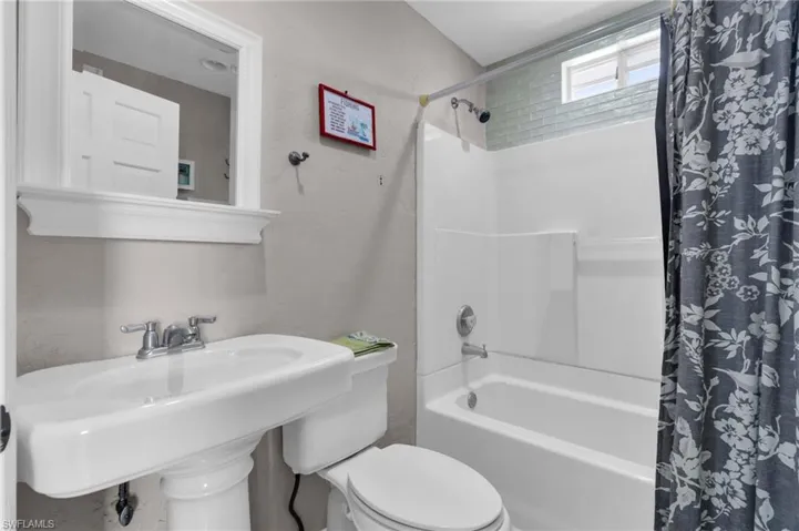 Bathroom featuring a sink, shower / bathtub combination with curtain, and toilet