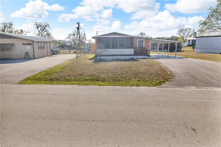 View of front of home with driveway, a carport, and a screened in patio
