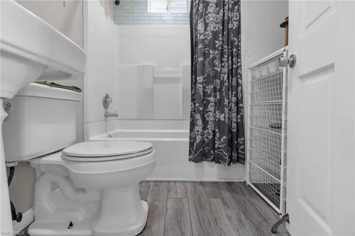 Full bathroom shower / tub combo with curtain, and toilet