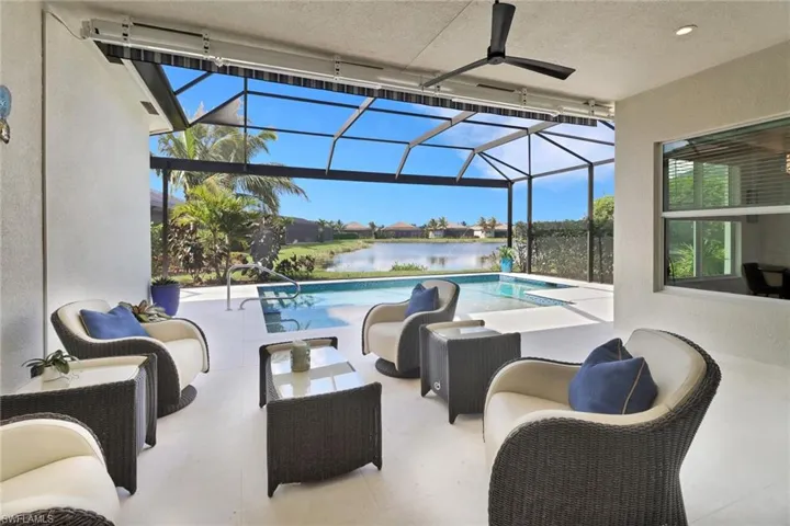 View of swimming pool with a patio area, glass enclosure, a water view, and ceiling fan
