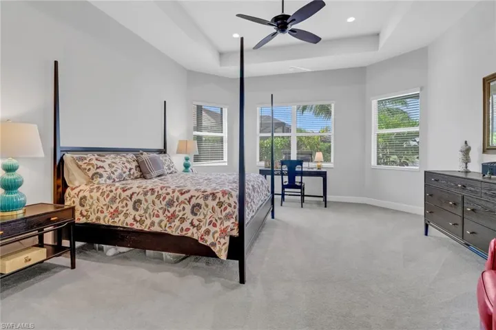 Carpeted bedroom with a tray ceiling and ceiling fan