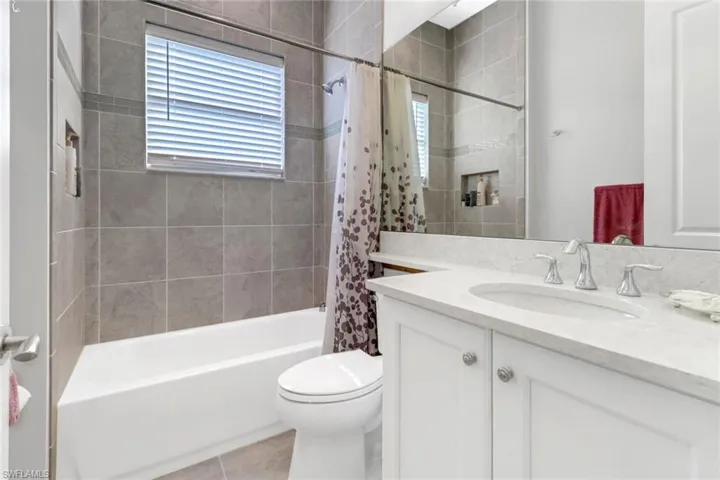 Full bathroom with vanity, shower / tub combo with curtain, toilet, and tile patterned floors