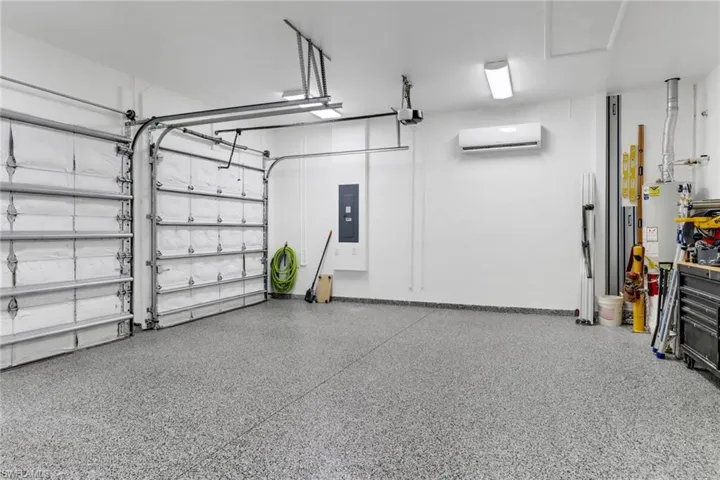 Garage featuring a garage door opener, a wall mounted AC, and electric panel