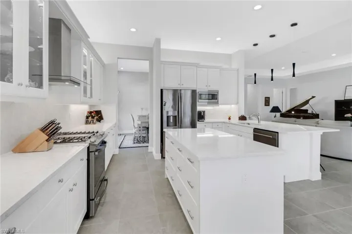 Kitchen featuring stainless steel appliances, sink, a center island, decorative light fixtures, and white cabinets