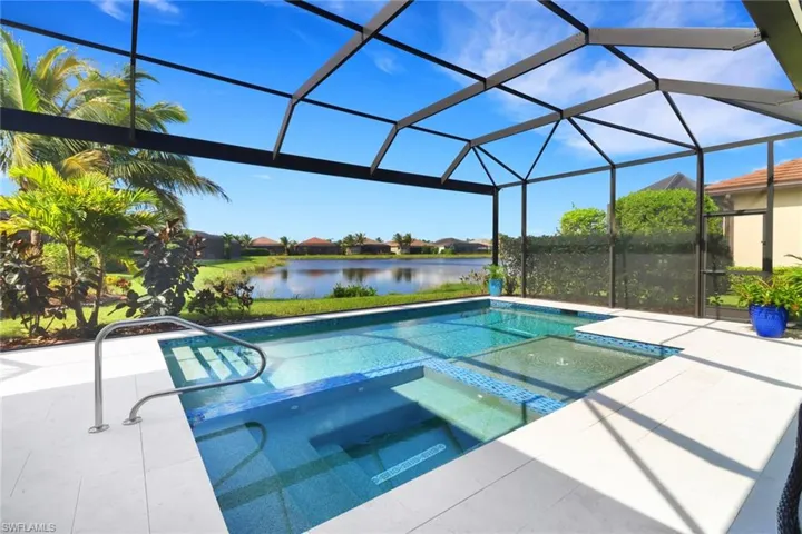 View of pool featuring a patio area, a lanai, an in ground hot tub, and a water view