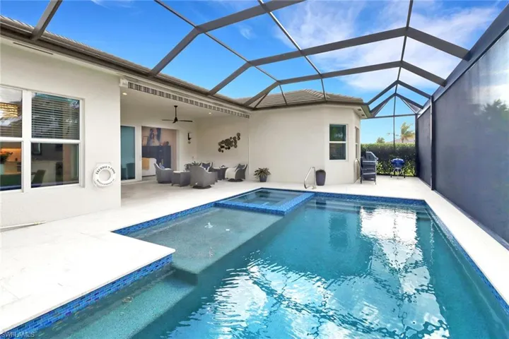 View of swimming pool featuring an in ground hot tub, ceiling fan, glass enclosure, and a patio area