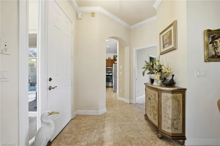 Foyer featuring arched walkways, crown molding, and light tile patterned floors