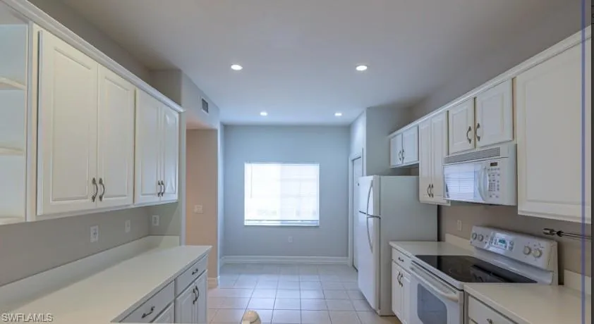 Kitchen with recessed lighting, white cabinets, white appliances, and light countertops