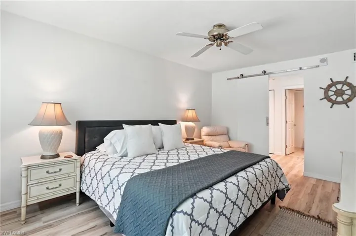 Bedroom with a barn door, wood finished floors, and a ceiling fan