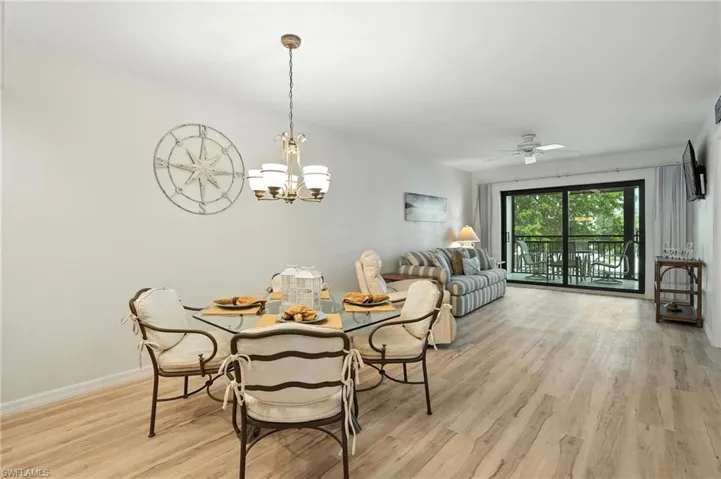 Dining space with light wood-style flooring, a chandelier, and a ceiling fan