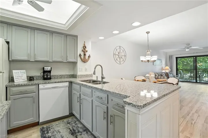Kitchen featuring dishwasher, ceiling fan, a peninsula, open floor plan, and light wood-type flooring