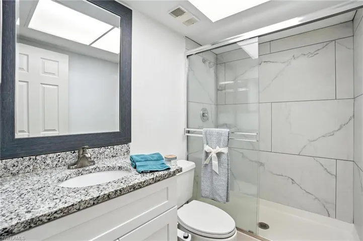 Bathroom with vanity and a marble finish shower