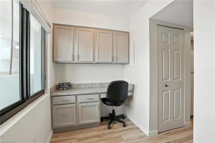 Office with built in desk and light wood-type flooring