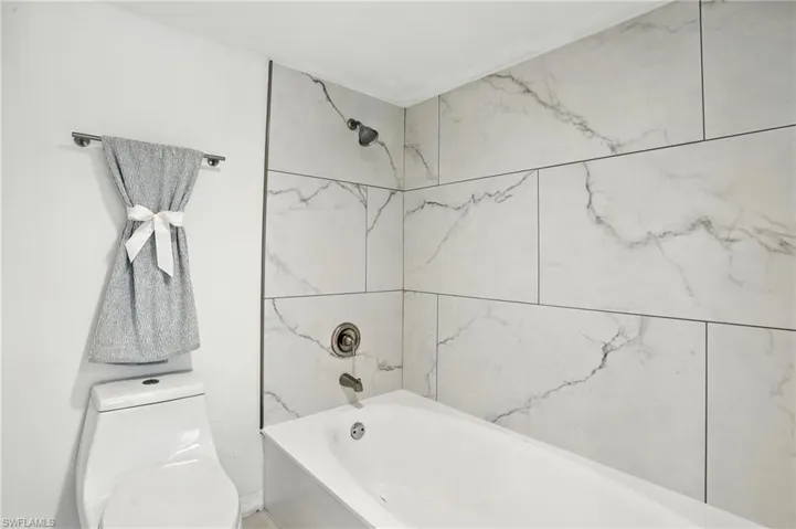 Full bathroom featuring washtub / shower combination and toilet