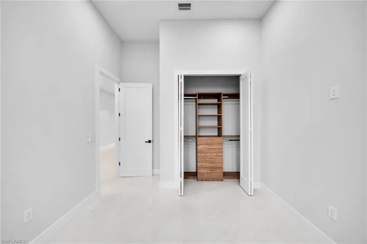 Integrated custom wood shelving and drawers in closet with white bi-fold doors